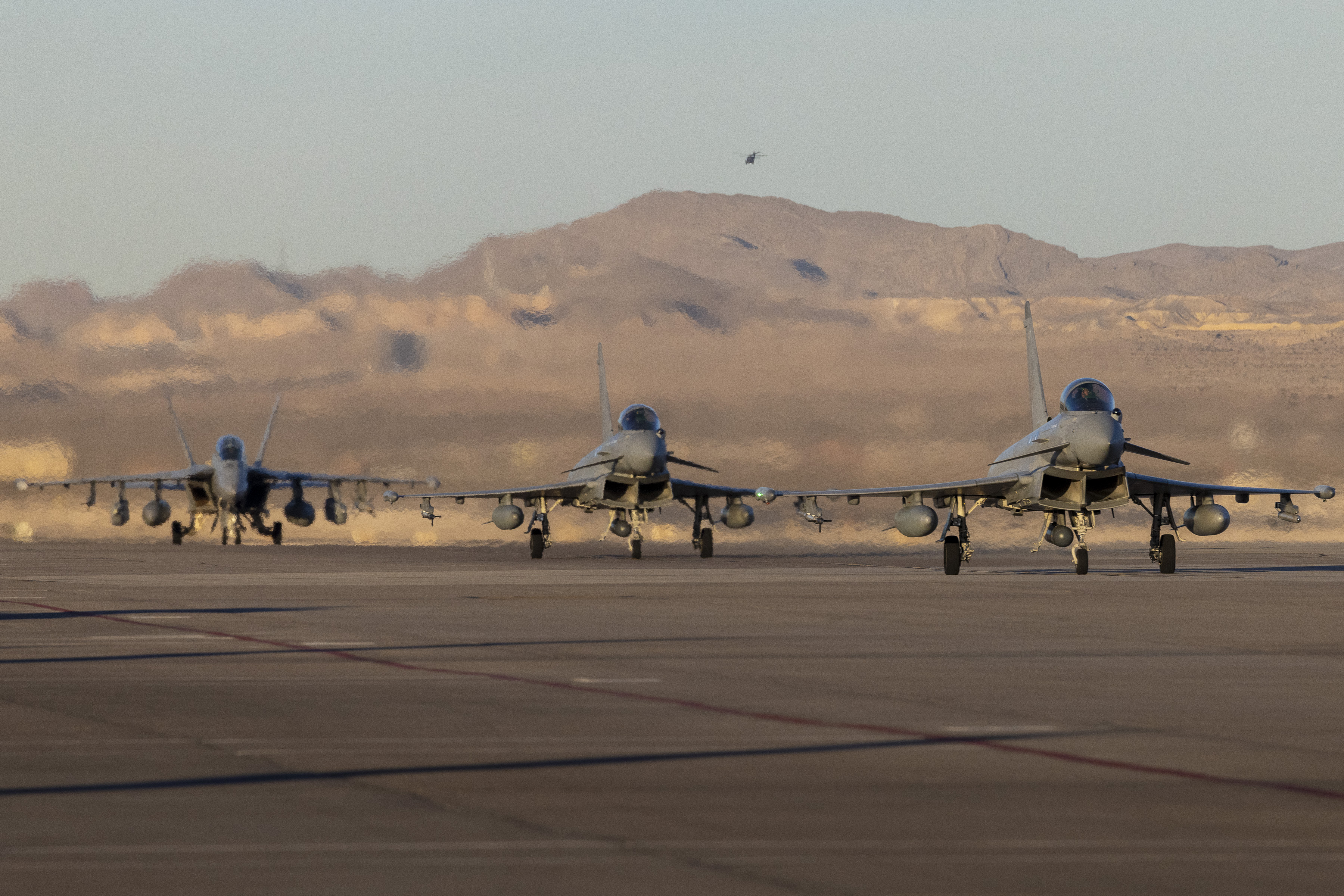 Image shows three RAF Typhoon aircraft rolling along on the airfield.